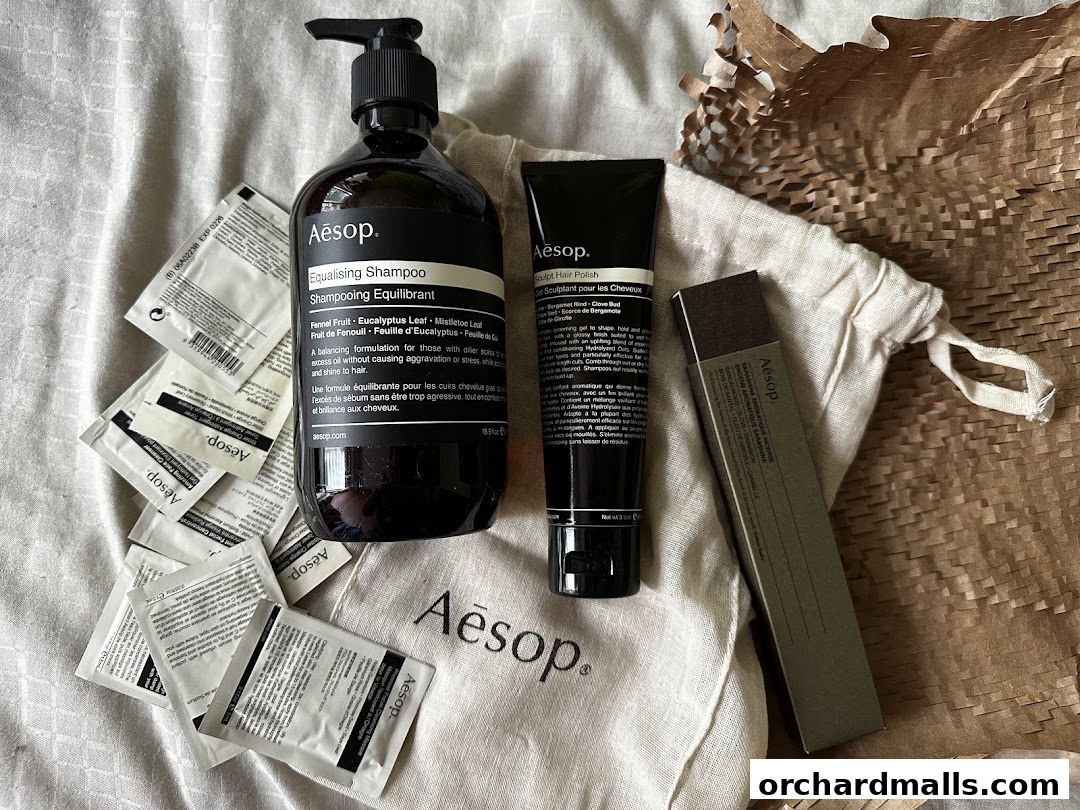 Aesop products including shampoo, hair polish, and samples laid out on a textured cloth.