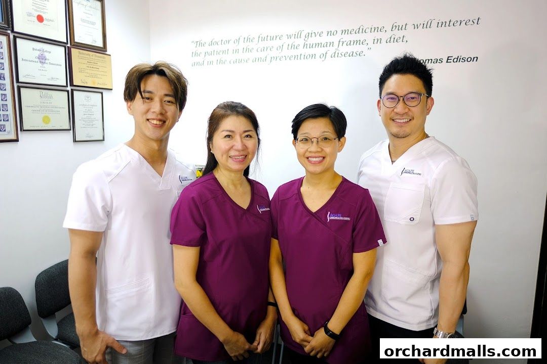 Four smiling healthcare professionals in scrubs stand together in a clinic.