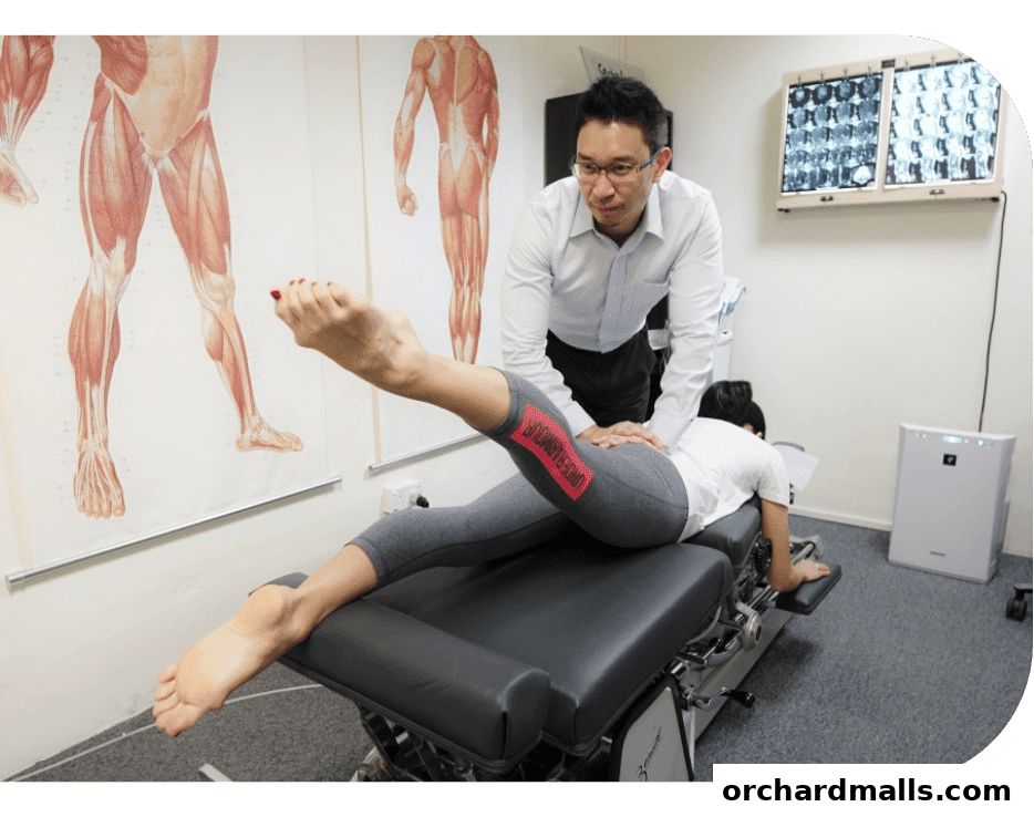 Chiropractor adjusting a patient on a treatment table with anatomical charts on the wall.