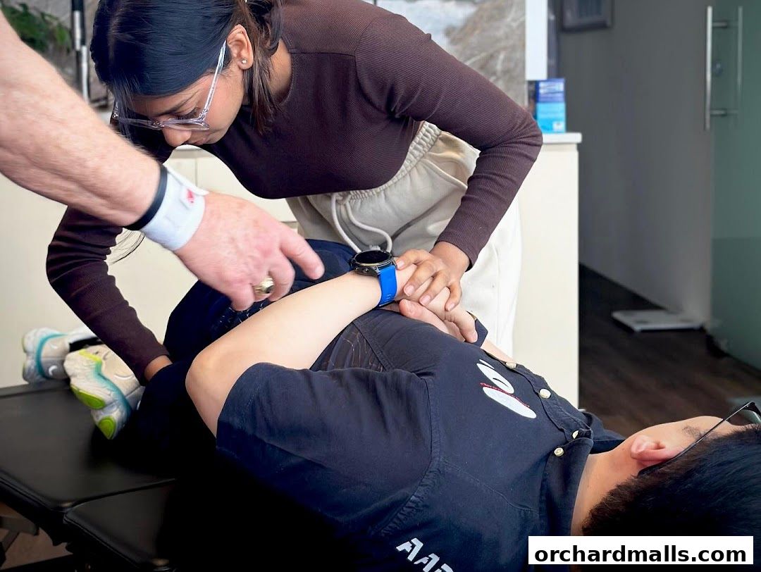 Chiropractor adjusting a patient's arm on a treatment table.