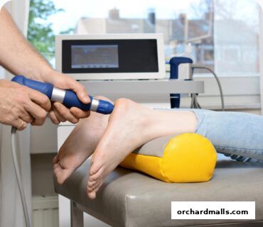 Chiropractor using therapeutic device on a patient's ankle.