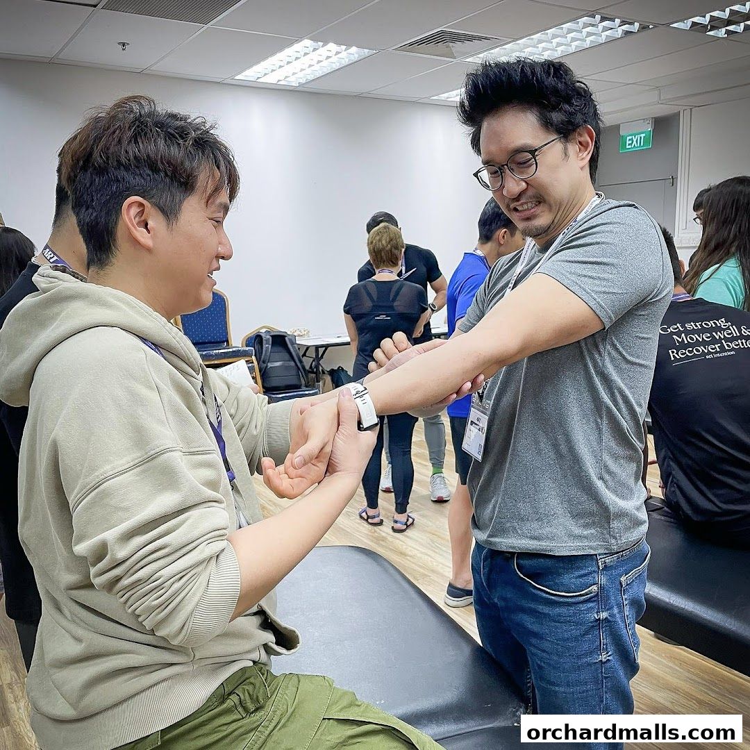 Chiropractor demonstrating a technique on a patient's wrist in a clinic setting.