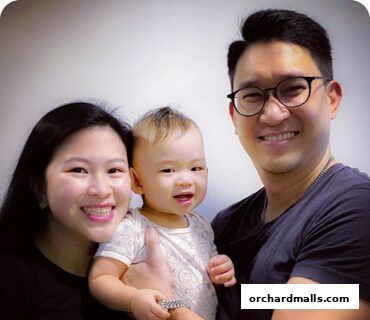 A smiling family of three, including a baby, posing for a photo.