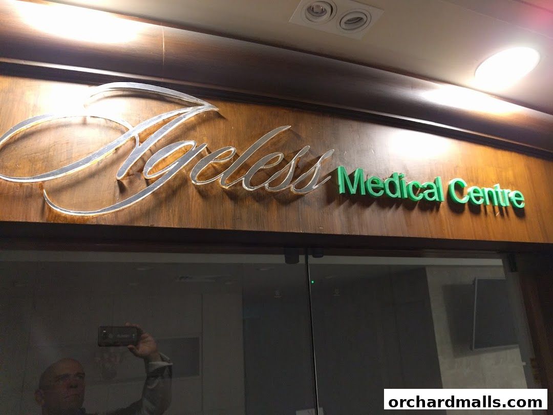 The sign for Ageless Medical Centre is displayed on a wooden panel above a glass entrance.