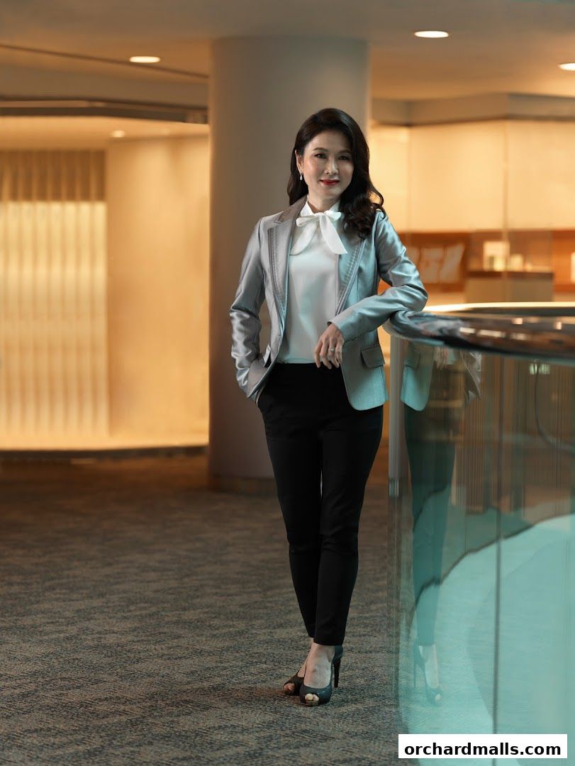 A professional woman in a silver blazer and black pants poses confidently.