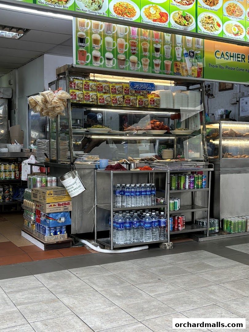 A food stall with a display of cooked food, drinks, and menu items.