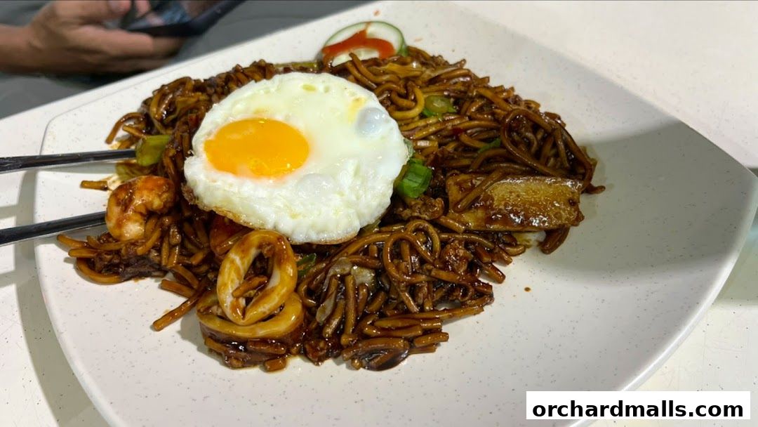 A plate of stir-fried noodles with a fried egg, shrimp, and squid.