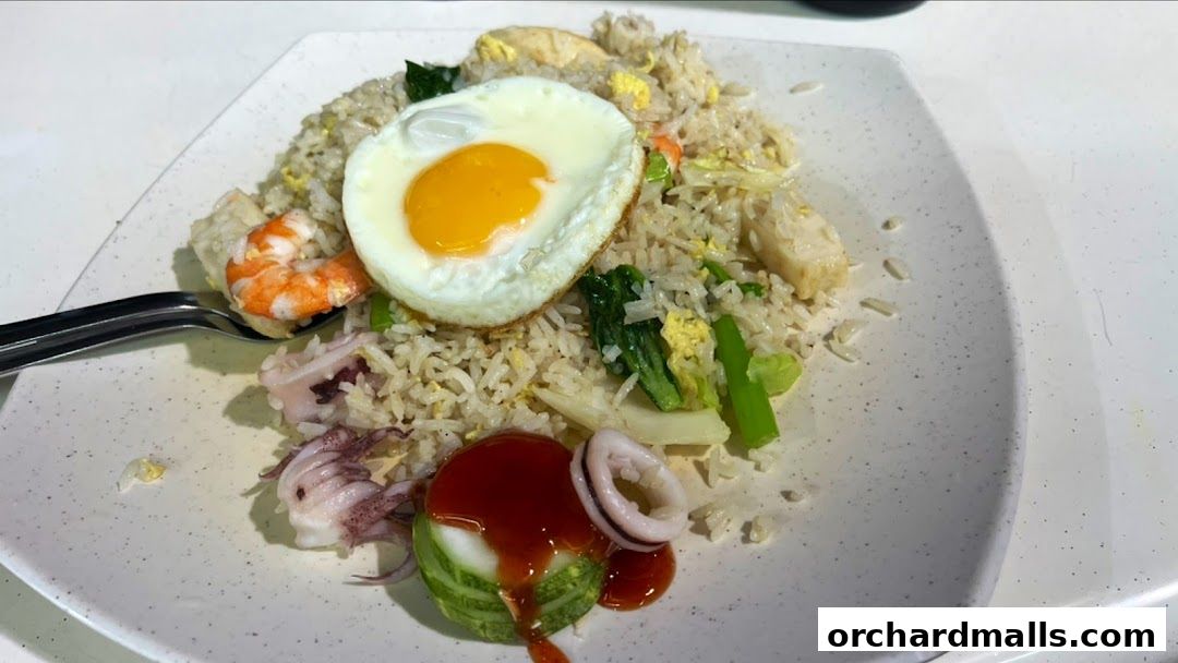 A plate of fried rice with a fried egg, shrimp, squid, and vegetables.