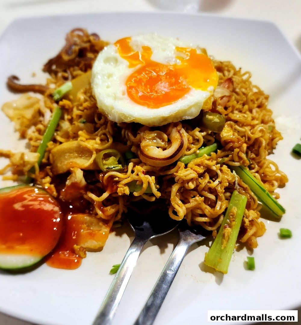 A plate of stir-fried noodles topped with a fried egg and squid.