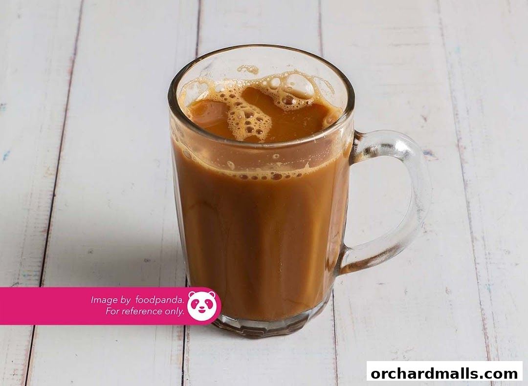 A refreshing glass mug filled with iced milk tea, topped with foam.