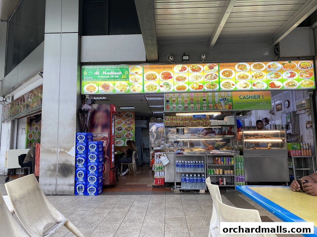 Exterior view of Al Madinah Restaurant with a large illuminated menu board showcasing various dishes.