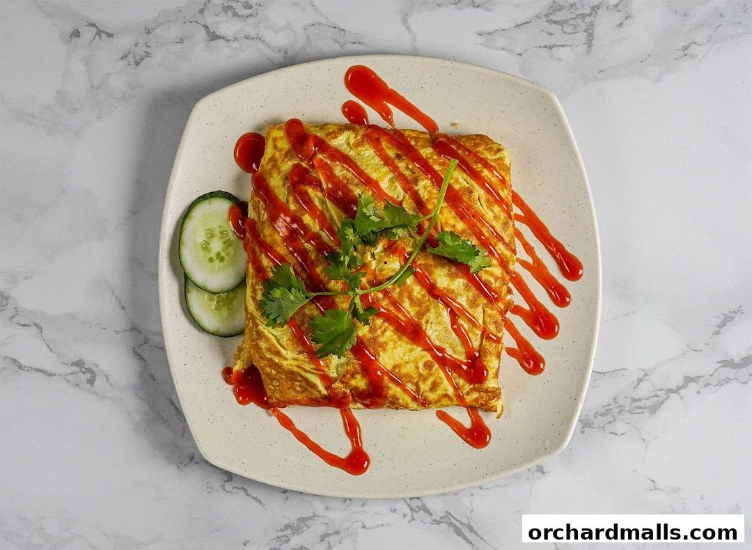 A square omelet drizzled with red sauce and garnished with cilantro and cucumber slices.