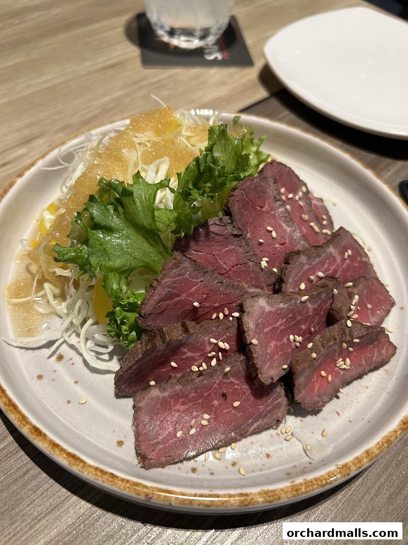 A plate of thinly sliced roast beef with a side salad and dressing.