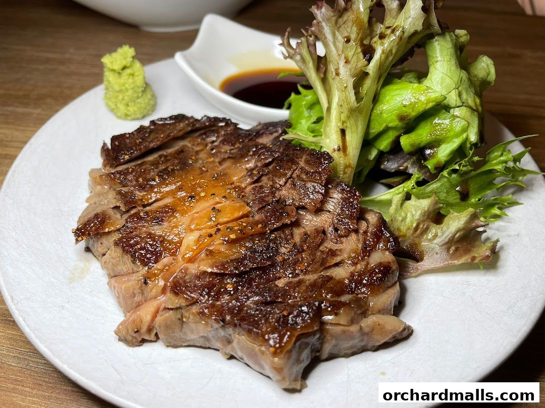 A succulent, sliced steak served with a side of fresh salad and wasabi.