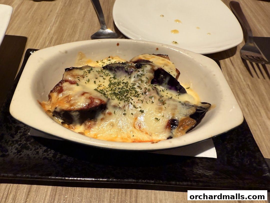 A close-up of a baked eggplant dish with melted cheese and herbs.