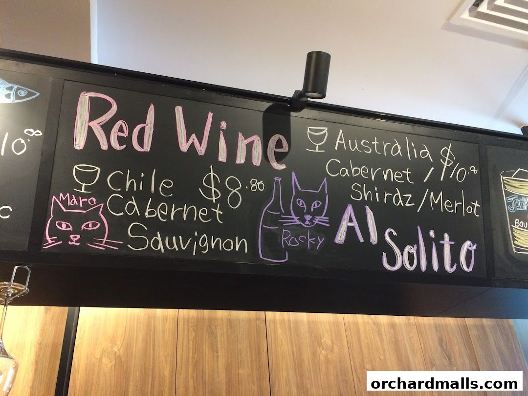 A chalkboard menu displays red wine selections with prices and origins.