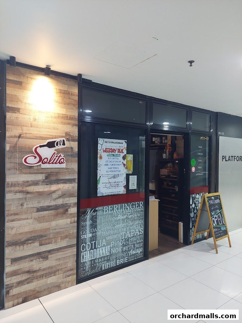 The entrance of AL Solito Japanese Italian izakaya, featuring a wooden facade and a display of wine and cheese names.
