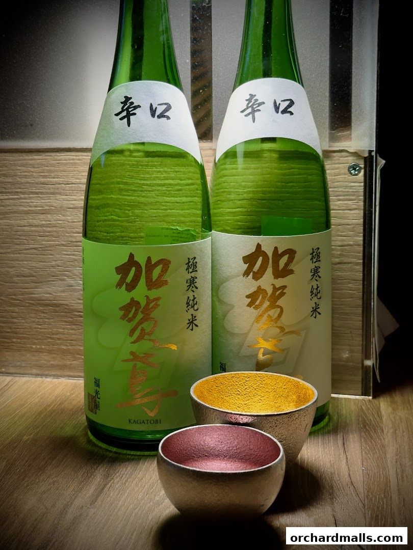 Two bottles of Japanese sake with traditional cups in front.