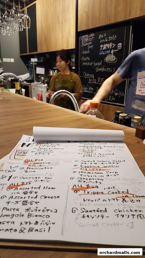 A menu with Japanese and Italian dishes is laid out on a wooden counter.