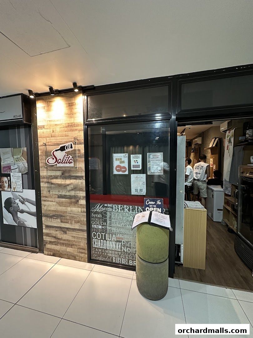 The entrance of AL Solito Japanese Italian izakaya, featuring a wooden facade and a glass door.