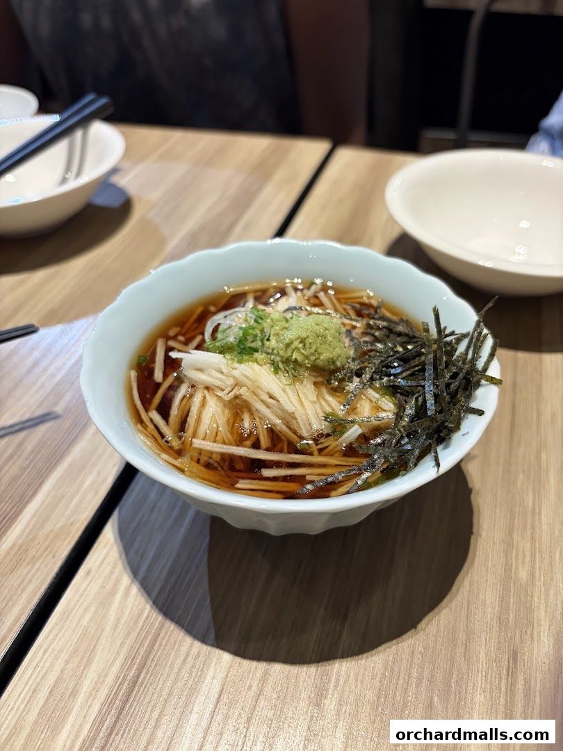 A bowl of Japanese soba noodles in broth with seaweed and wasabi.