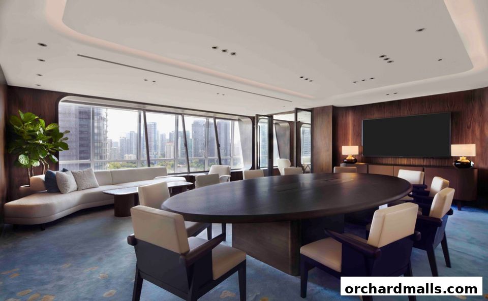 A modern conference room with a large oval table, comfortable seating, and city views.