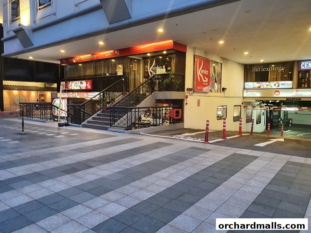 Exterior view of a massage, reflexology, and spa shop with a parking entrance nearby.