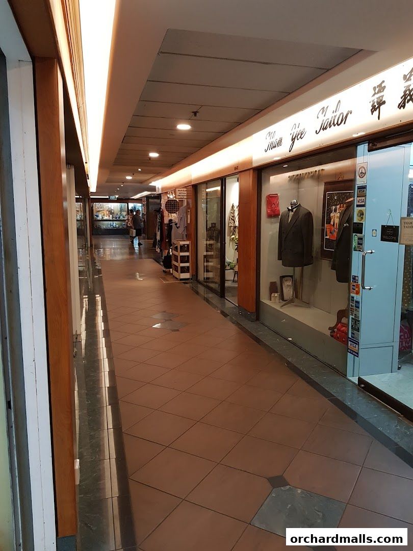 A tailor shop with mannequins displaying suits and a sign that reads 'Sham Yee Tailor'.