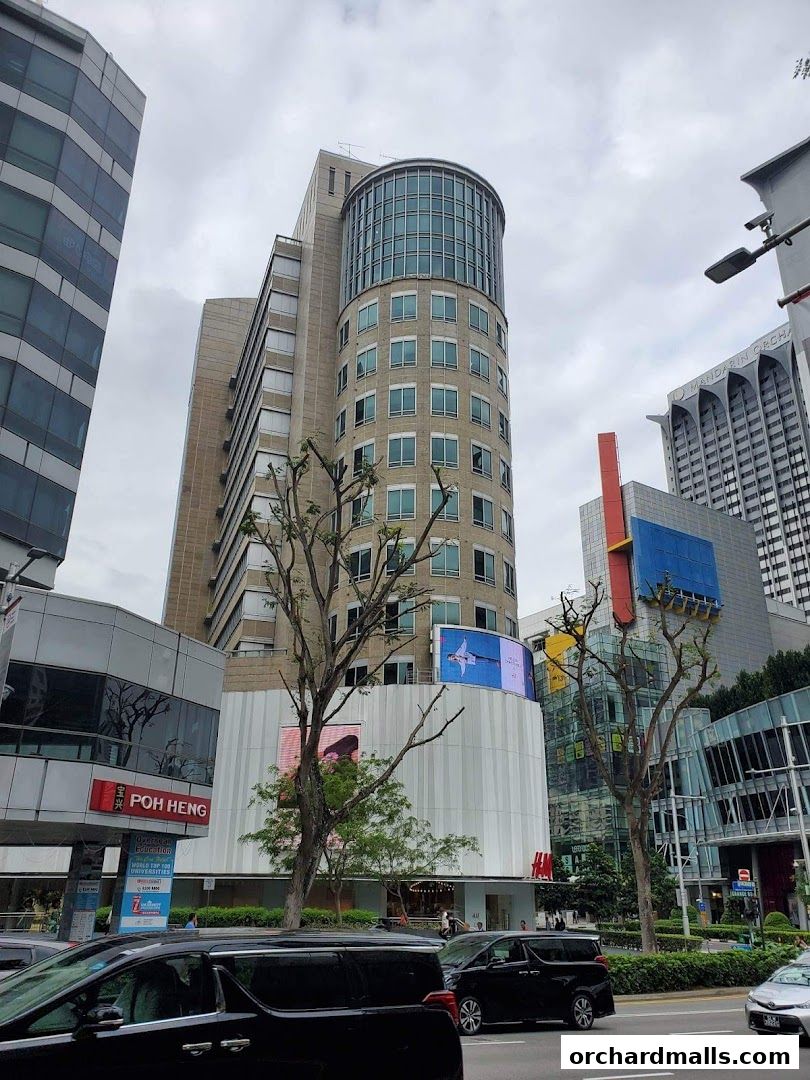A modern building with a curved glass section and retail stores on the ground floor.