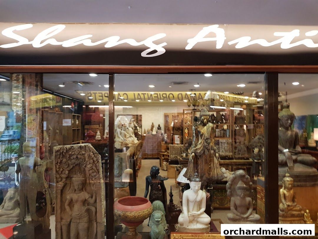 Shop window display of Shang Antiques featuring various statues and artifacts.