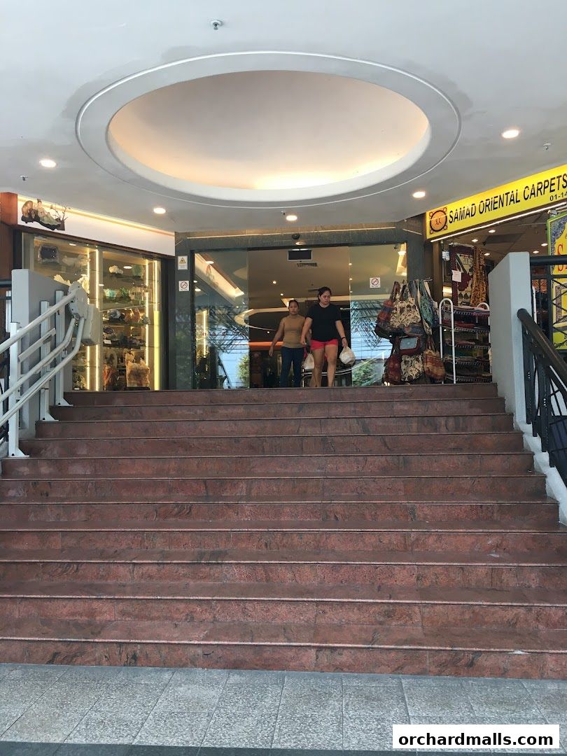 Entrance to Andric Leasing with a carpet shop next door and display of goods.