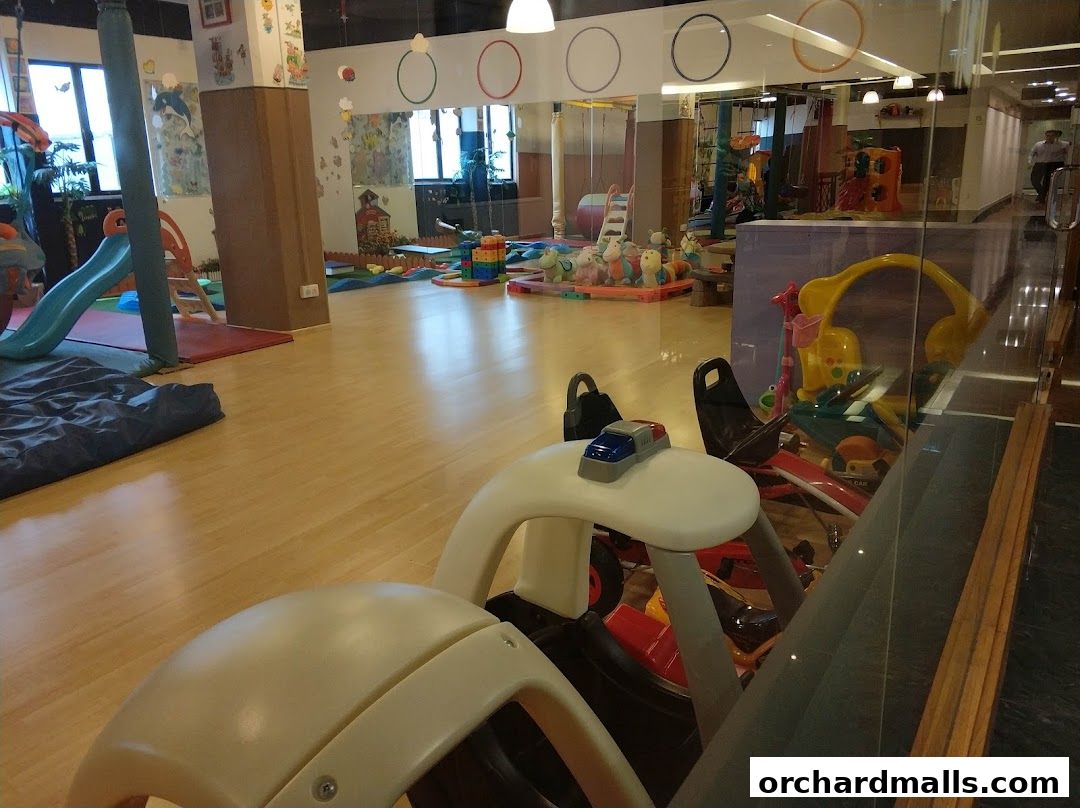 A brightly lit indoor play area for children with slides, toys, and play structures.