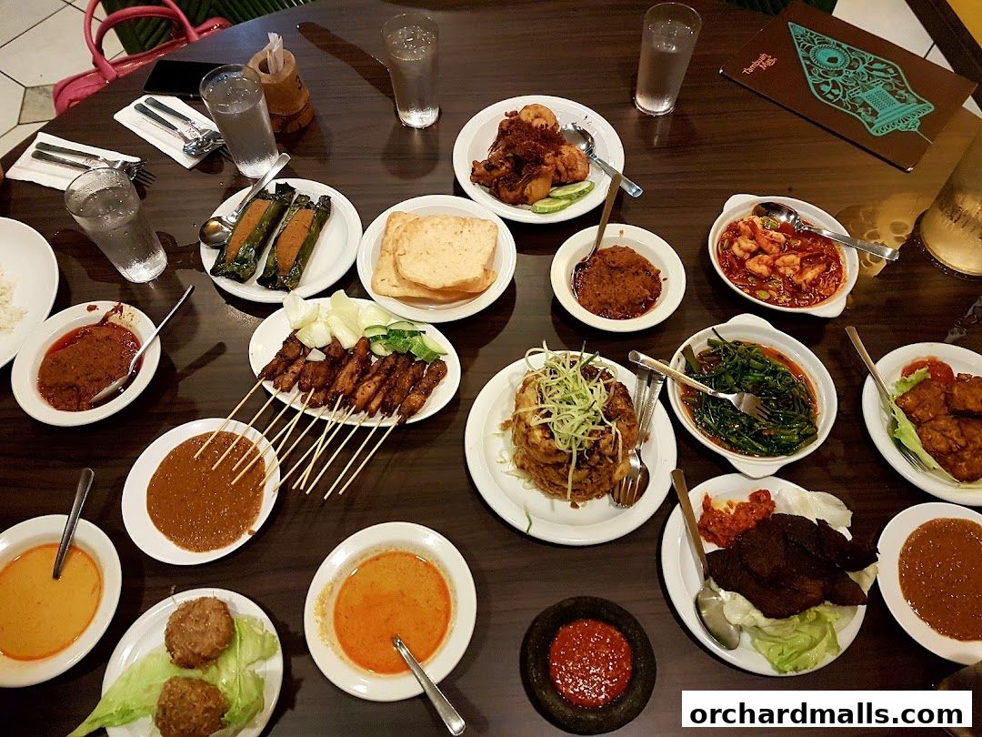 A table laden with various Indonesian dishes, including satay, curries, and stir-fried vegetables.