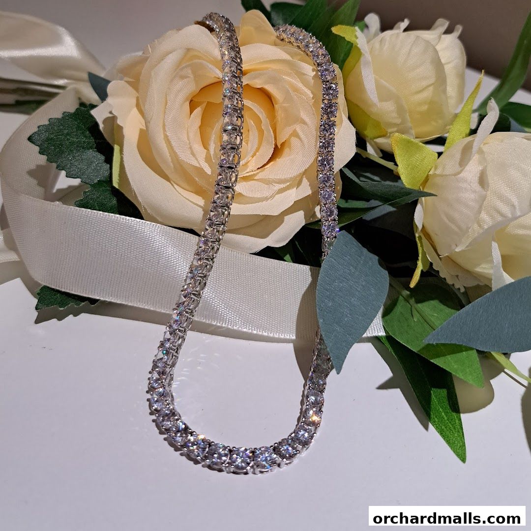 A sparkling diamond necklace displayed with elegant cream roses and a satin ribbon.