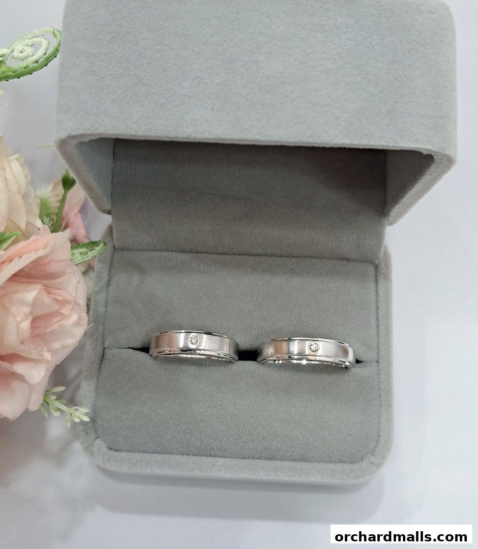 A pair of elegant silver rings with small diamonds in a velvet ring box.