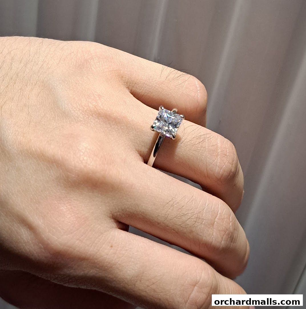 A hand wearing a princess-cut diamond engagement ring.