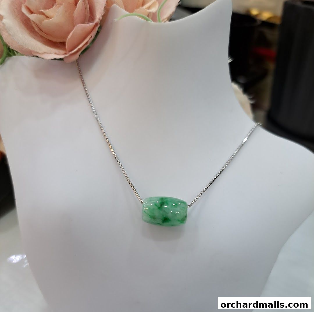 A jade bead necklace displayed on a white mannequin bust with pink roses.