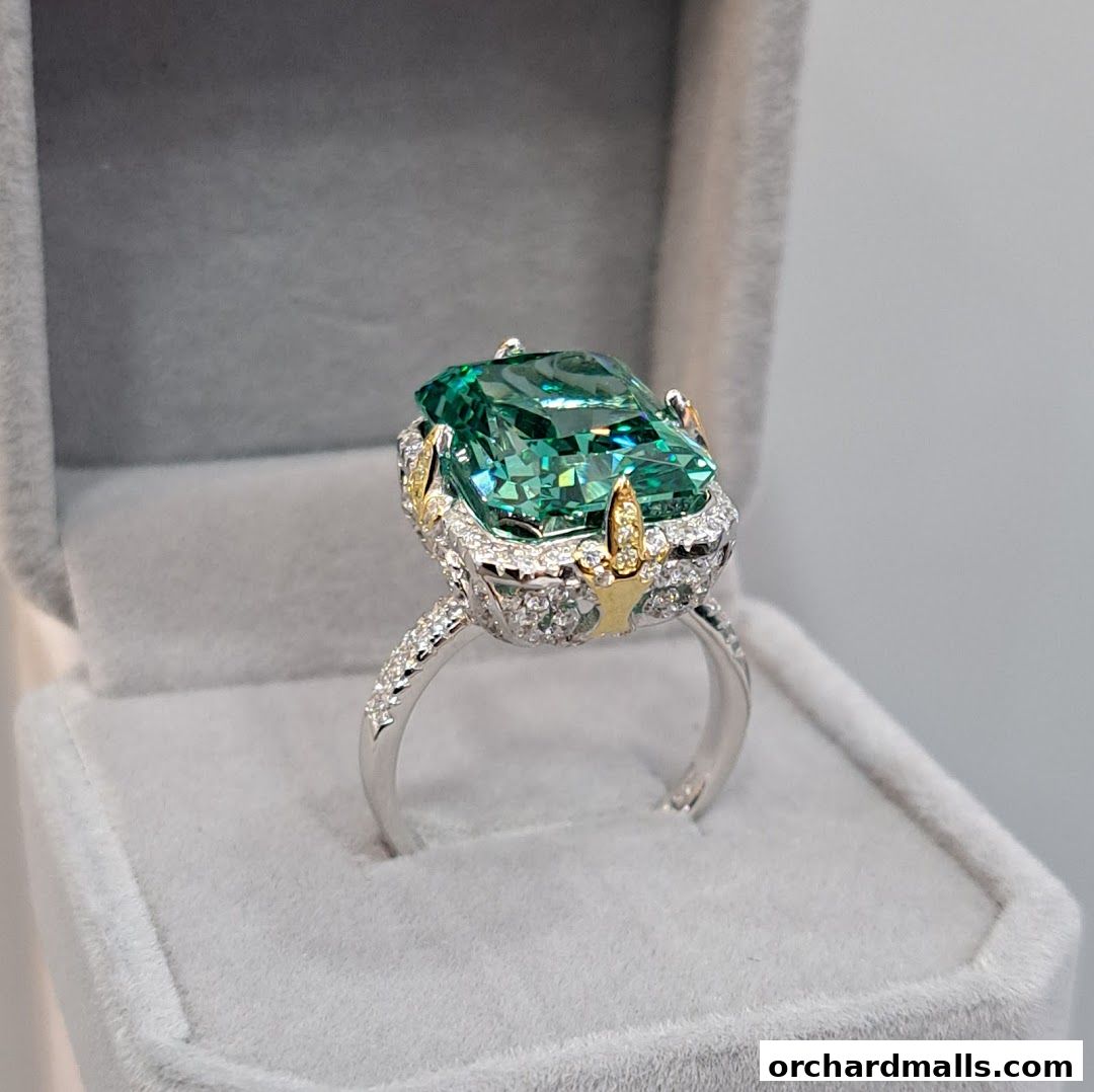 A stunning emerald-cut green gemstone ring with diamond accents in a velvet box.