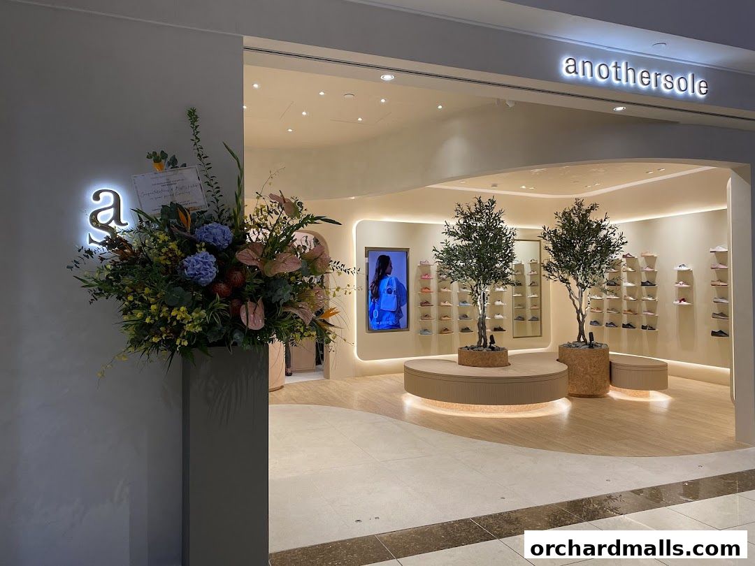 The entrance of the Anothersole shoe store with a large floral arrangement and display of shoes.