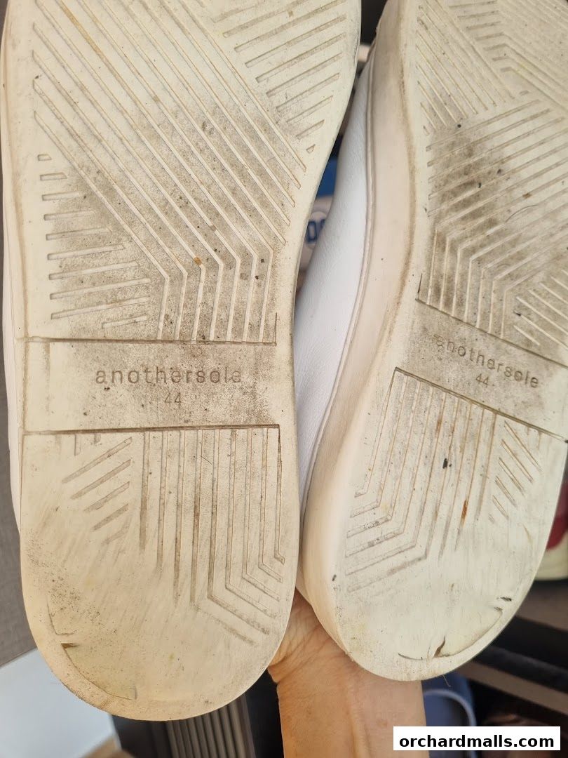 Close-up of the soles of two white Anothersole shoes, size 44.