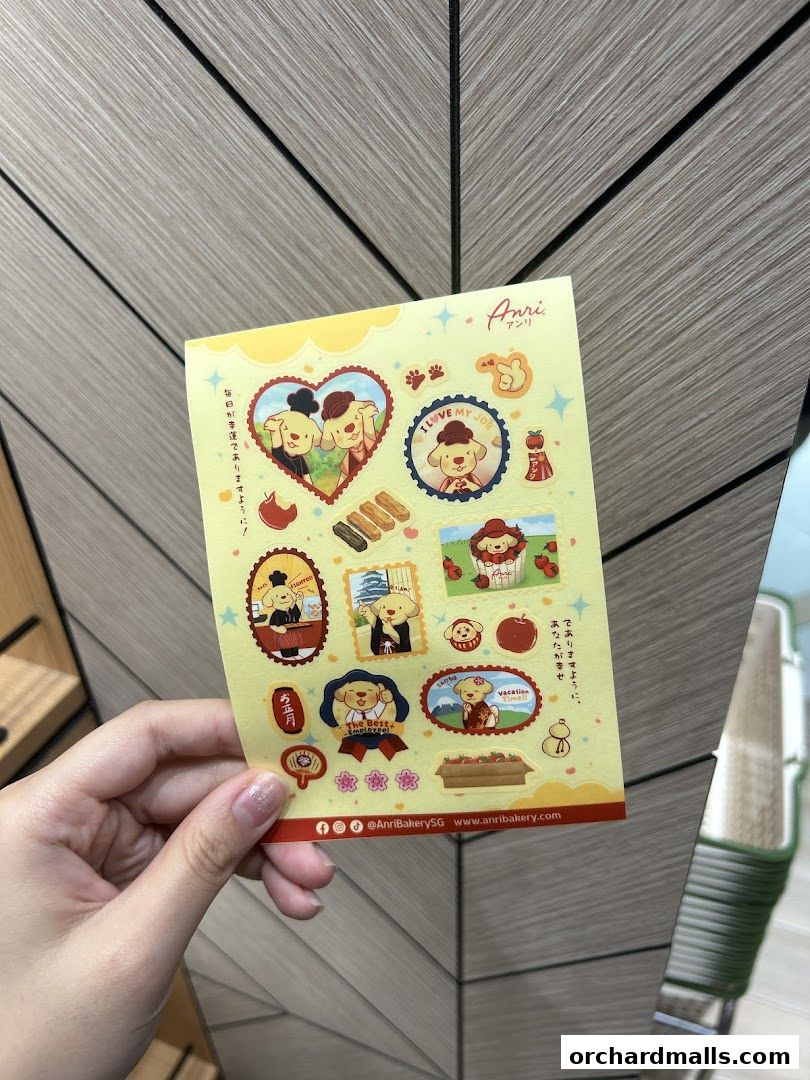 A hand holds a sheet of cute dog-themed stickers from Anri Bakery.