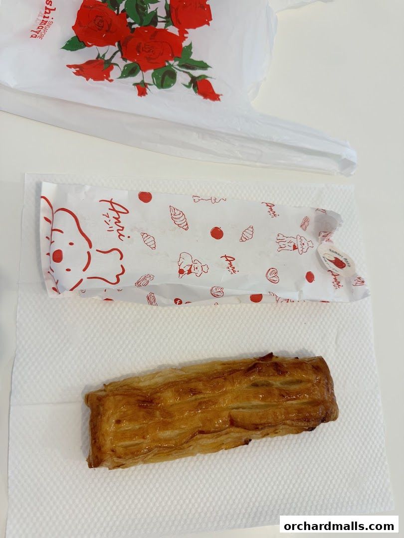 A golden-brown pastry sits on a white napkin next to Anri branded packaging.