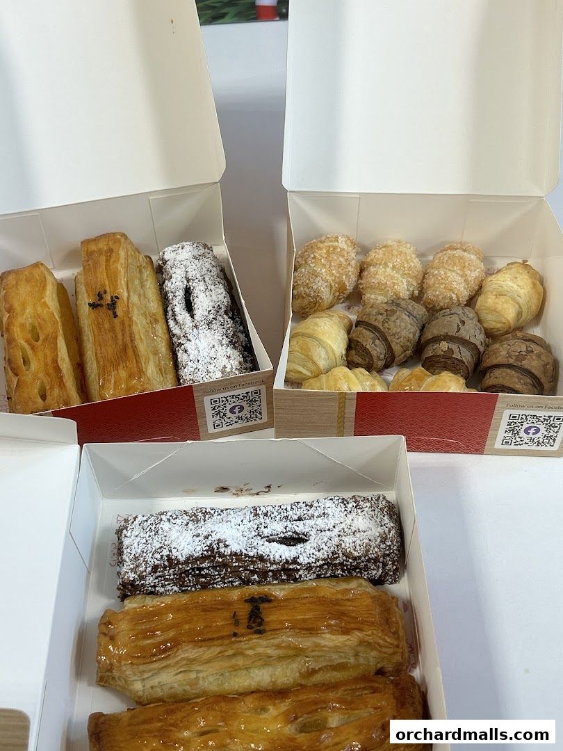 Boxes of assorted pastries, including croissants and filled rolls, ready for takeaway.