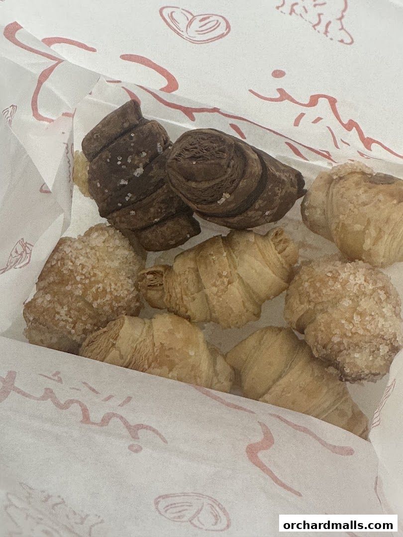 A close-up shot of assorted mini croissants in a branded paper bag.