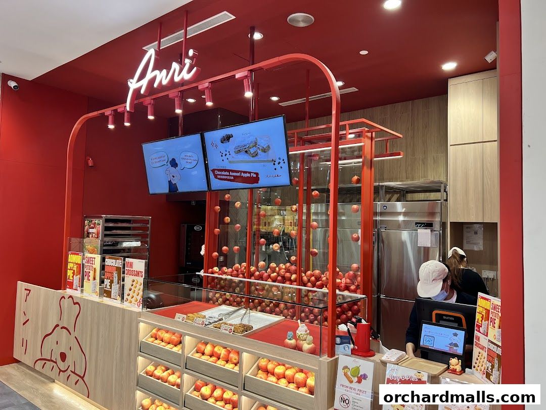 A bright red Anri shop interior with a display of apples and baked goods.