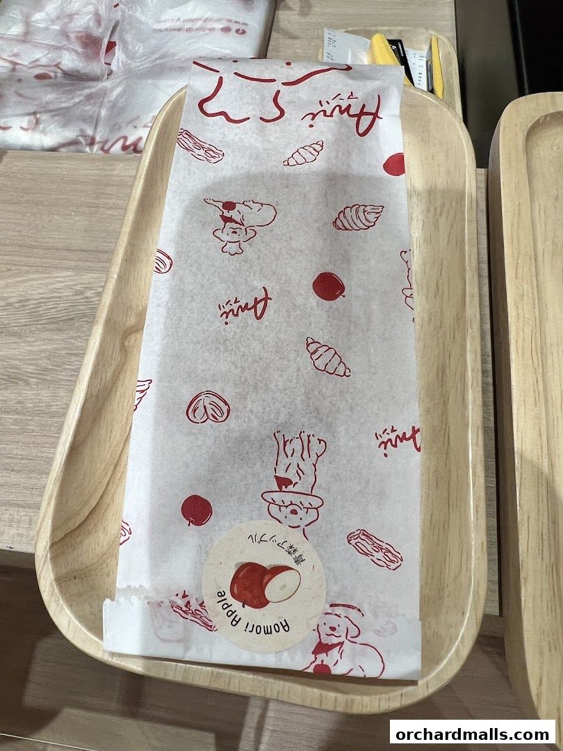 A pastry wrapped in branded paper sits on a wooden tray.