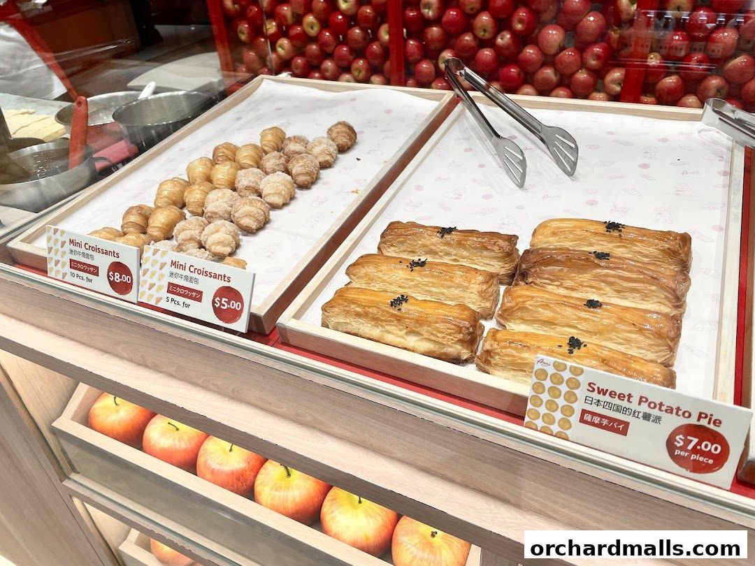 A display of freshly baked mini croissants and sweet potato pies at a bakery.
