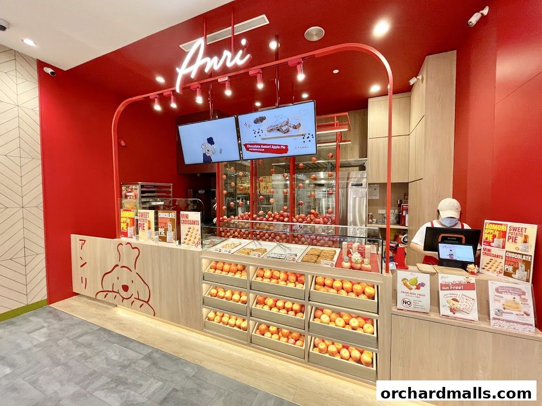 The Anri shop front displays fresh apples and baked goods with a vibrant red and wood interior.