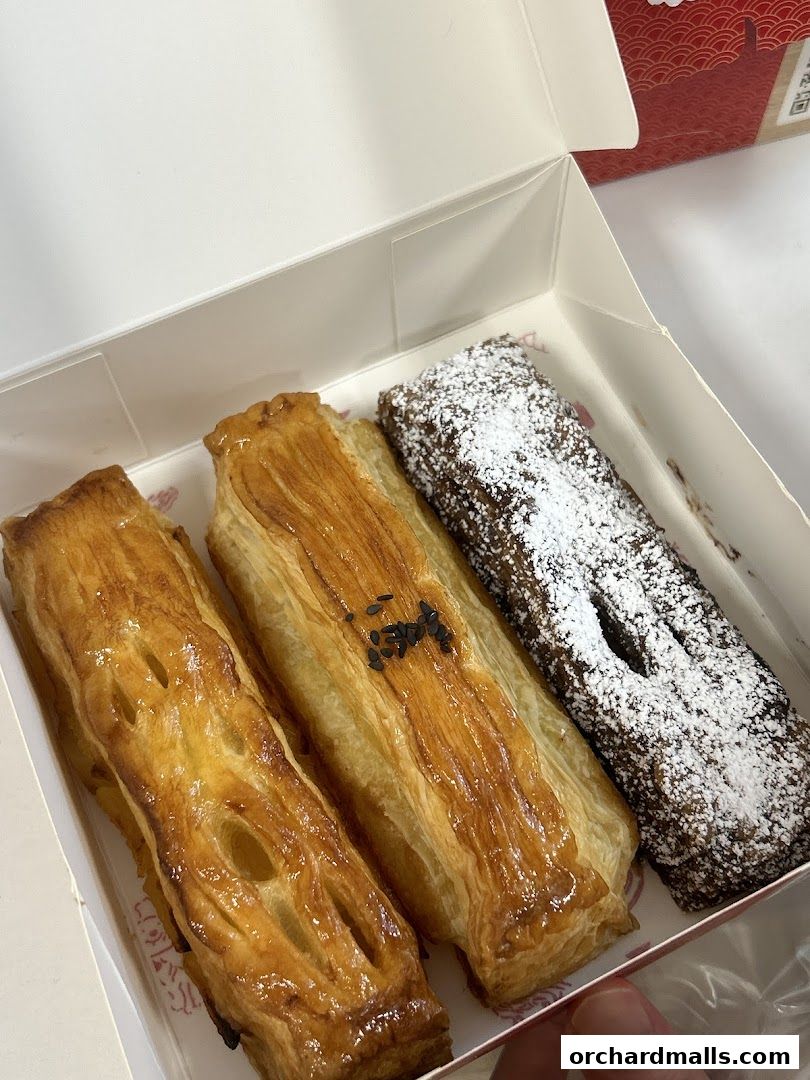 A box of three delicious pastries, two golden brown and one dusted with powdered sugar.