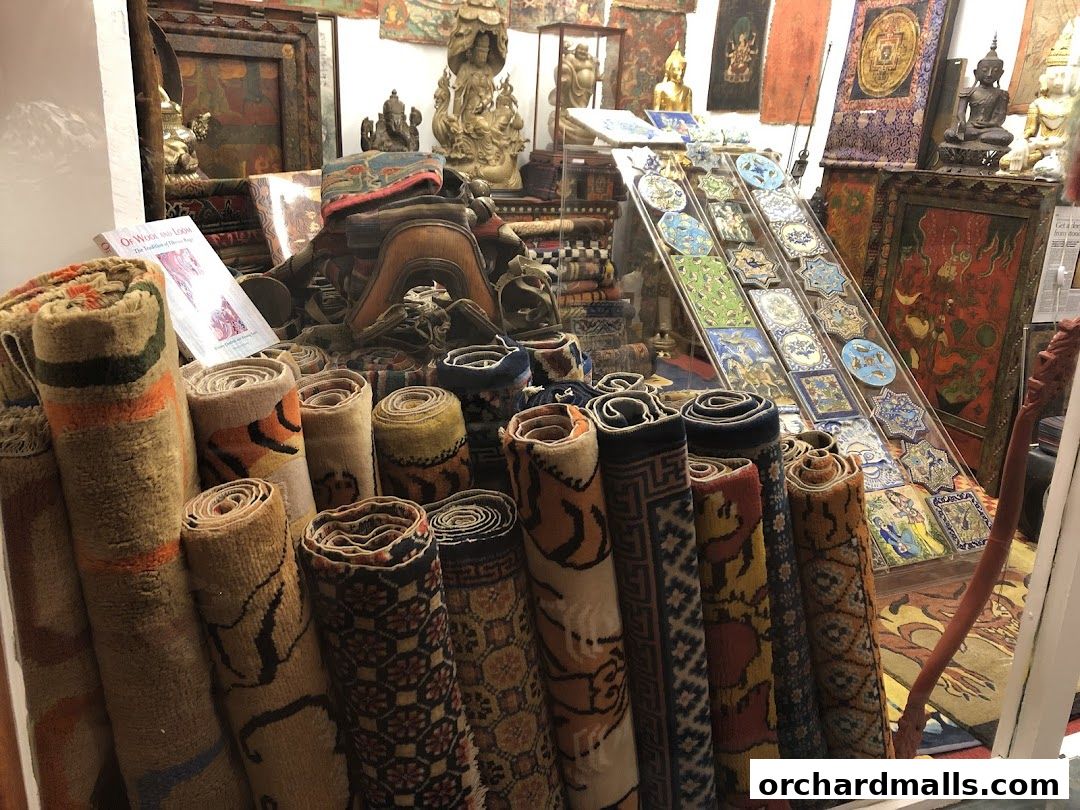 A shop interior filled with rolled carpets, artwork, and decorative items.